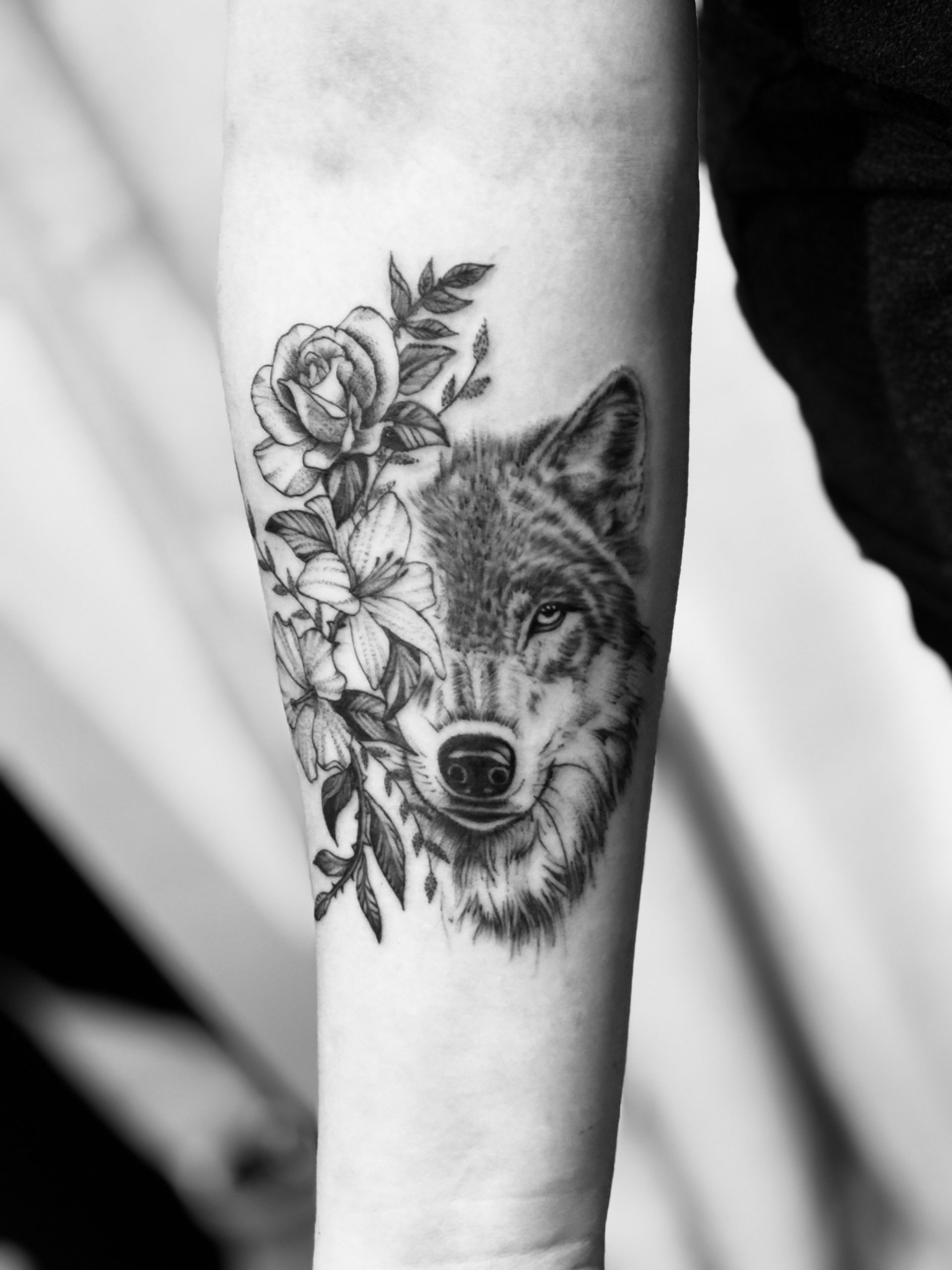 Tattoo: Wolf mit Rosen und Lilien am Unterarm